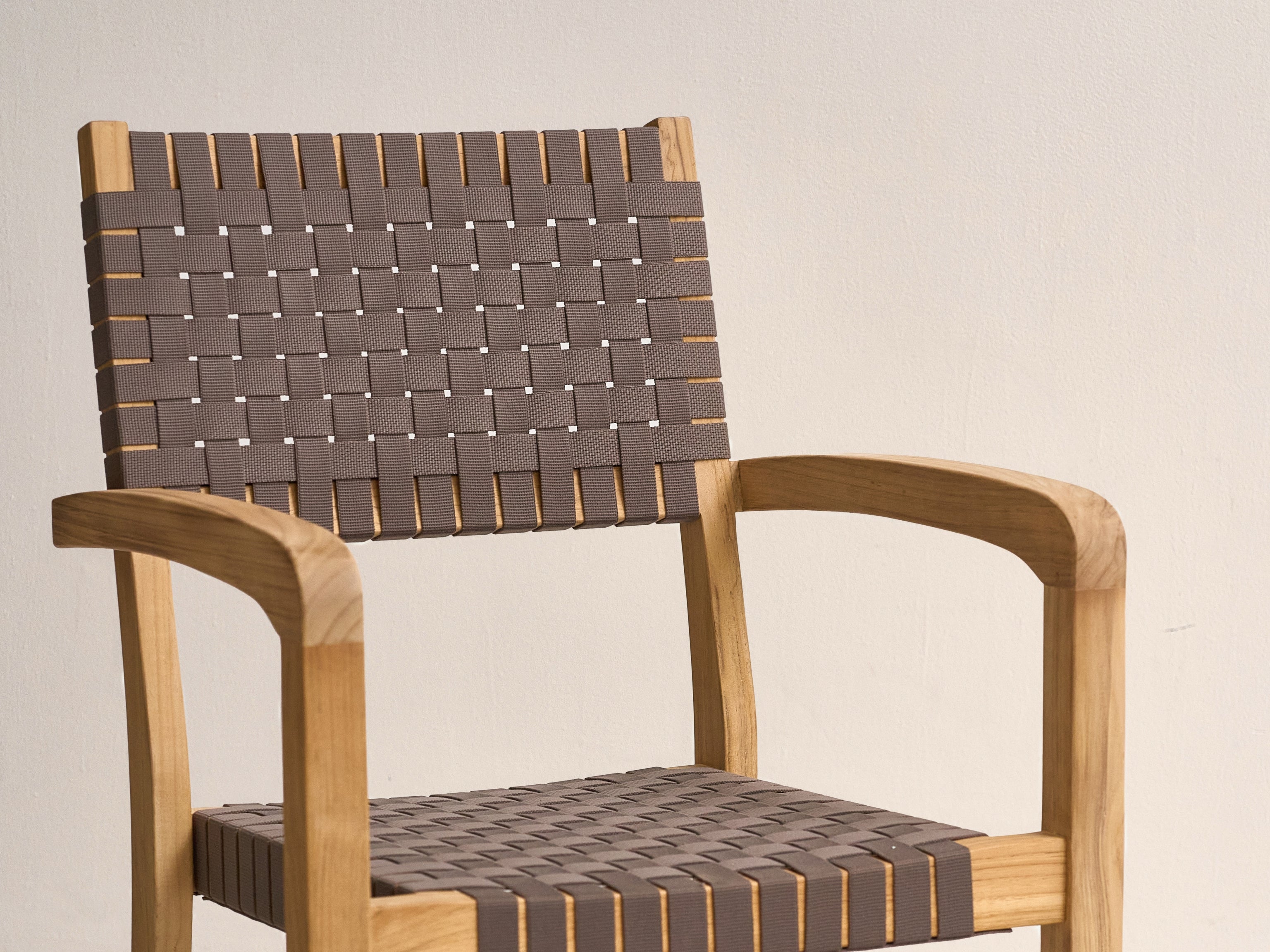 Clairene teak dining armchair with woven strap seat, angled view